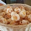 A basket full of light, sunny-yellow round cheese rolls, each a mouthful
