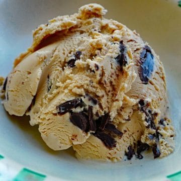 A scoop of coffee ice cream with large, irregularly shaped chunks of chocolate