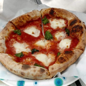Small puffy-crusted pizza is topped with mozzarella, tomato sauce, and basil