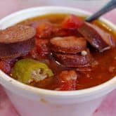 Crowded styrofoam cup of gumbo holds plenty of sausage, as well as okra, tomatoes, and peppers