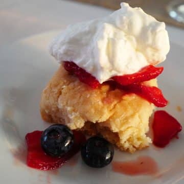 Fruits and whipped cream top a buttermilk biscuit