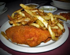 Chicken breast with red-gold crust shares plate with French fries.