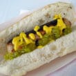 Bunned white hot dog dressed with mustard and relish