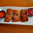 6 breaded and deep-fried ravioli are accompanied by two red dipping sauces.
