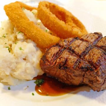 Plate holds filet mignon, mashed potatoes, onion rings ... best beef